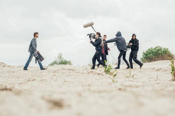A group of people on the beach with one person holding a camera.